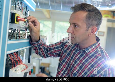 uomo che installa un cavo in fibra ottica in fabbrica Foto Stock