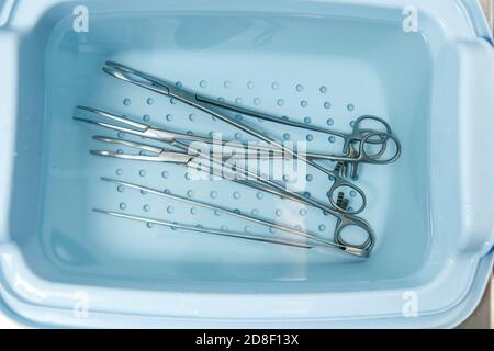 Gli strumenti chirurgici vengono risciacquati in un vassoio con acqua. Disinfezione di apparecchiature mediche Foto Stock