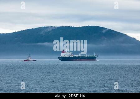 Un cargo del petrolio che è scortato da un rimorchiatore a sud dell'isola di Cypress nelle isole di San Juan in una giornata nuvolosa, Rosario Strait, Washington, USA. Foto Stock