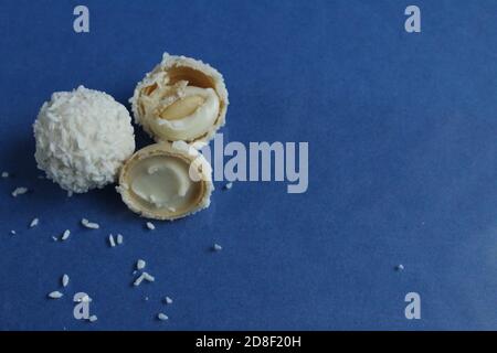 tre bianchi con caramelle al cocco e metà con waffle E crema bianca come Raffaello su sfondo blu e luminoso con spazio di copia per il testo Foto Stock