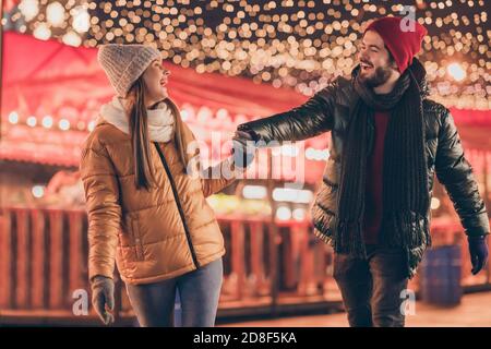 Foto di coppia passeggiata natale sera fiera tenere mani godere x-mas noel illuminazione esterna indossare camici di stagione Foto Stock