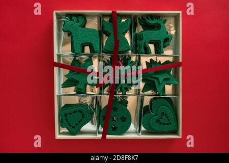 Kraft felt giocattoli verdi in scatola - pronto regalo fatto in casa. Decorazioni natalizie su superficie rossa. Vista dall'alto, disposizione piatta Foto Stock