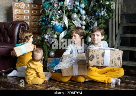 Felici i fratelli bambini che aprono i regali davanti all'albero di Natale. Tempo di Natale. Concentratevi sul bambino. Foto Stock