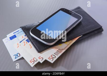 Di banconote in euro in borsa e lo smartphone su sfondo grigio Foto Stock