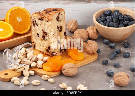 Tipo di pane dolce panettone di Milano - Italia di solito preparato e gustato a Natale e Capodanno servito su un tavolo con arancio, pistacchio, valnu Foto Stock