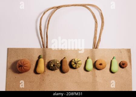 Foto concettuale dello shopping delle zucche biologiche. Piccole zucche fatte a mano su sacchetto di carta marrone. Foto Stock