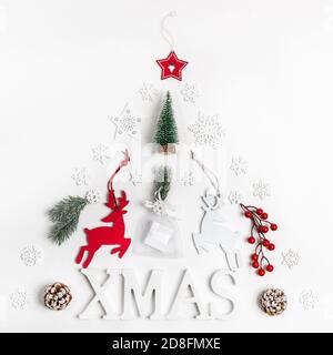 Decorazioni natalizie: Lettere XMAS, cervi, ramoscelli d'abete, bacche, fiocchi di neve, regalo fai da te allestito come albero di Natale su bianco. Foto Stock