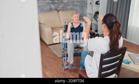 Vecchia donna non valida in sedia a rotelle che fa addestramento di riabilitazione con il supporto dal medico. Disabile anziano ricoverato infermiera di aiuto professionale, cura di casa di riposo e riabilitazione Foto Stock