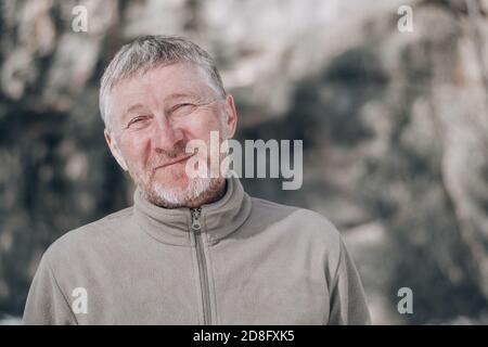 Ritratto di un uomo di mezza età all'aperto, bello e felice, non rasato. Guarda la fotocamera con un sorriso. Concetto di persone e stile di vita. Spazio per il testo. Foto Stock