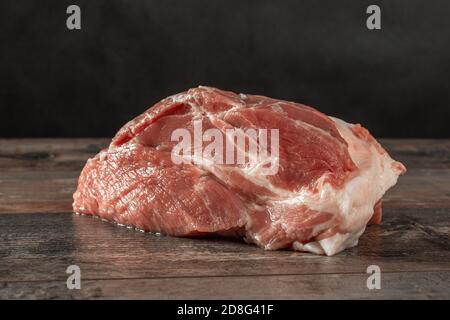 Carne CRUDA su fondo di legno scuro. Carne di maiale cruda su tavola rustica di legno è pronta per la cottura. Carne fresca nel macellaio Foto Stock