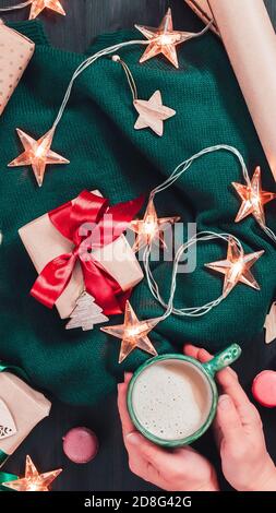 Appartamento di Natale con scatole regalo artigianali, luci di ghirlanda e decorazioni su sfondo di legno scuro. Formato verticale per dispositivi mobili Foto Stock