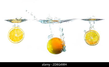 le arance fresche si tuffano in acqua su sfondo bianco Foto Stock