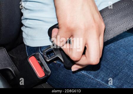 Primo piano di una mano femmina caucasica che tiene una fibbia della cintura di sicurezza per il fissaggio in auto. Concetto di sicurezza dell'auto Foto Stock