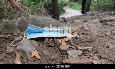 Immagine di una maschera facciale gettata a terra un parco Foto Stock