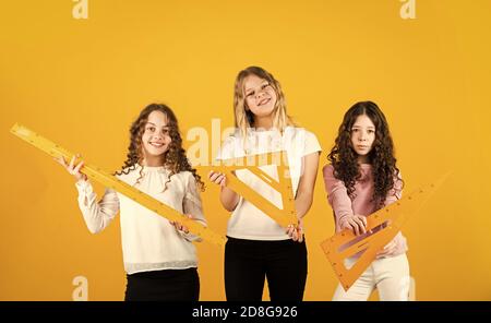 Studenti che si preparano agli esami. Sisterhood. Tre ragazze con triangolo e righello. Torna a scuola. Discipline della scuola STEM. Concetto di matematica e di persone. Forme geometriche. Concetto di istruzione moderna. Foto Stock