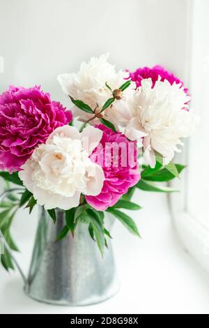 Bouquet di belle peonie in giardino. Peonie rosa e bianche in una caraffa di stagno. Messa a fuoco morbida - immagine Foto Stock