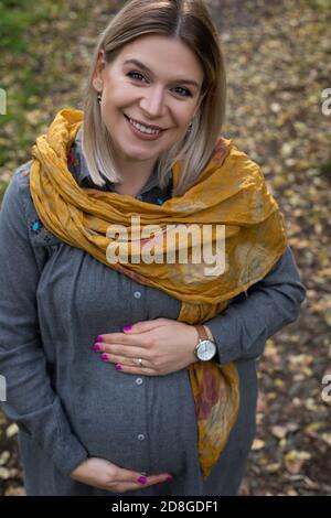 Ritratto di affascinante donna caucasica incinta nella terza spesa di trimestre tempo all'aperto in una scena autunnale Foto Stock