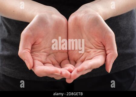 Mani di una giovane donna, mani vuote, a forma di tazza, in primo piano, che chiedono qualcosa Foto Stock