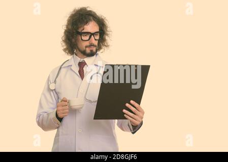 Studio shot di uomo bello medico lettura su appunti mantenendo tazza da caffè Foto Stock