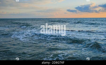 Aumento marea freddo blu scuro onde con schiuma di mare in nuvoloso cattivo tempo invernale fickle. Cambiamento di stagione, tema di riscaldamento globale, turismo invernale. Foto Stock