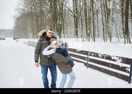 La famiglia felice ha un divertimento fuori vicino alla casa in inverno. Vacanza in famiglia e concetto di tempo felice Foto Stock