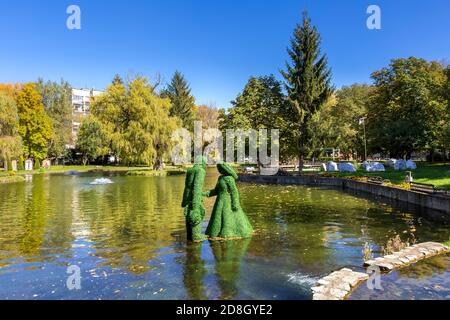 Razlog, Bulgaria - 20 ottobre 2020: Lago, uomo e donna verde foglie figurine vista panoramica con alberi d'autunno e fontane Foto Stock