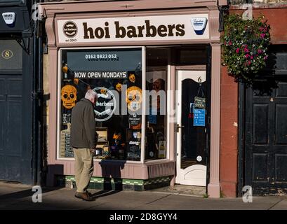 East Lothian, Scozia, Regno Unito, 30 ottobre 2020. Decorazioni di Halloween: Un uomo anziano che guarda nella finestra di un barbiere a Haddington con decorazioni di Halloween Foto Stock