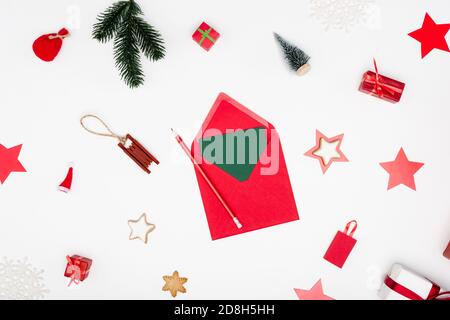 vista dall'alto della busta rossa con cartoncino e matita vicino baubles di natale e stelle al forno su bianco Foto Stock