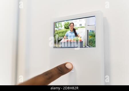 Uomo africano che usa il sistema di sicurezza di ingresso video intercom Foto Stock