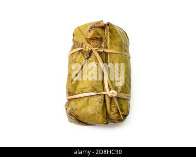 Il primo piano di riso thai al vapore appiccicoso con latte di cocco e banana (Khao Tom Mud) avvolto da foglie di banana su sfondo bianco. Foto Stock
