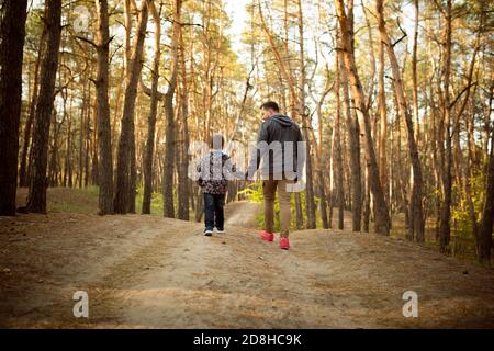 Caldo. Padre e figlio che camminano e si divertono nella foresta d'autunno, sembrano felici e sinceri. Laughting, giocare, avere buon tempo insieme. Concetto di famiglia, felicità, vacanze, infanzia, stile di vita. Foto Stock