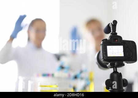 La fotocamera cattura i blogger chimici femminili che agita in sostanze chimiche primo piano del laboratorio Foto Stock