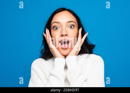 donna sorpresa con bocca aperta guardando la fotocamera isolata blu Foto Stock
