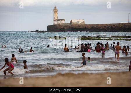 I beachgoers nuotano vicino ad un faro sull'isolotto di Santa Maria a Praia, Santiago, Capo Verde. Foto Stock