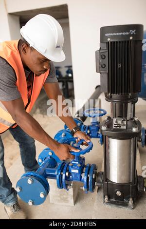 Un lavoratore maschile professionista gestisce una nuova valvola per attrezzature presso un serbatoio dell'acqua e una stazione di pompaggio sull'isola di Maio, Cabo Verde. Foto Stock