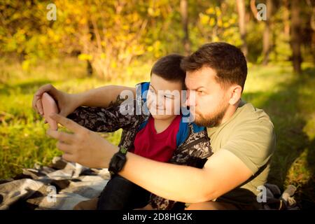 Selfie. Padre e figlio che camminano e si divertono nella foresta d'autunno, sembrano felici e sinceri. Laughting, giocare, avere buon tempo insieme. Concetto di famiglia, felicità, vacanze, infanzia, stile di vita. Foto Stock