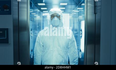 Scienziato Virologo Factory Worker in tuta tuta si disinfetta in camera doccia decontaminazione. Risposta di emergenza a rischio biologico. Foto Stock