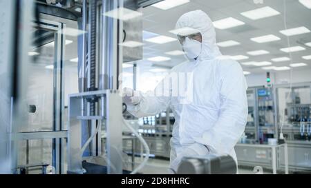 In stabilimento di produzione Shot of Scientist in indumenti protettivi sterili lavoro su un moderno industriale 3D macchina di stampa. Farmaceutico Foto Stock