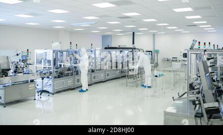 Shot of Sterile High Precision Manufacturing Laboratory dove gli scienziati della tuta protettiva utilizzano computer e microscopi, facendo prodotti farmaceutici Foto Stock