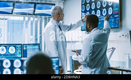 Il team di scienziati lavora nel Brain Research Laboratory, discutendo Brain Scans Show su Wall TV Monitor. Neurologi neuroscienziati Foto Stock