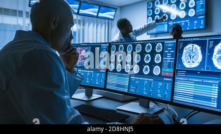 Over the Shoulder Shot di Senior Medical Scientist che lavora con immagini TAC Brain Scan su un personal computer in laboratorio. Neurologi in Ricerca Foto Stock