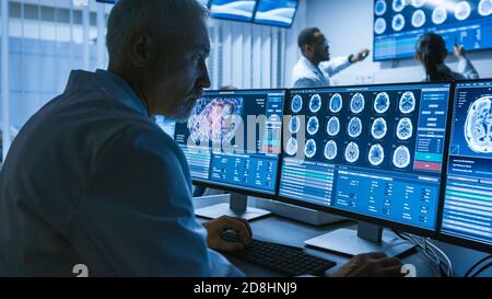 Over the Shoulder Shot di Senior Medical Scientist che lavora con immagini TAC Brain Scan su un personal computer in laboratorio. Neurologi in Ricerca Foto Stock