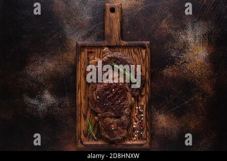 Bistecca di manzo alla griglia con spezie su tavola di legno, vista dall'alto. Foto Stock