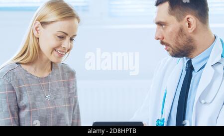 Bella Femminile visite Dottore's Office, mostra Tablet computer con la sua storia medica che discutono la sua salute e altri problemi medici. Moderno Foto Stock