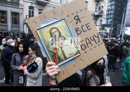 Un manifestante detiene un cartello con le immagini di Gesù Cristo durante la manifestazione al di fuori della Corte costituzionale di Kiev.il 27 ottobre, la Corte costituzionale aveva deliberato sull'incostituzionalità di alcune disposizioni della legge sulla prevenzione della corruzione e dell'articolo 366-1 del Codice penale dell'Ucraina, che prevede la dichiarazione di responsabilità per attività imprecise. L'Unione europea può sospendere i viaggi senza visto con l'Ucraina dopo che la Corte costituzionale del paese ha violato gli impegni anticorruzione del governo nei confronti dell'Europa, secondo il capo della missione Ucraina presso l'Unione europea Mykola Foto Stock