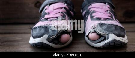 Usurati vecchie scarpe con i fori nelle dita del piede usato da bambini senza tetto Foto Stock