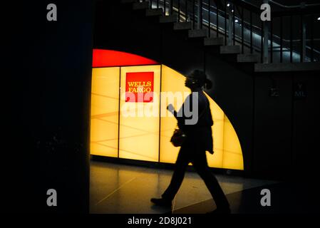 I viaggiatori camminano oltre il logo Wells Fargo a Penn Station, New York City, USA. Foto Stock