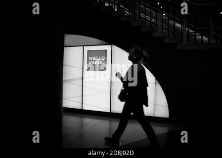 I viaggiatori camminano oltre il logo Wells Fargo a Penn Station, New York City, USA. Foto Stock