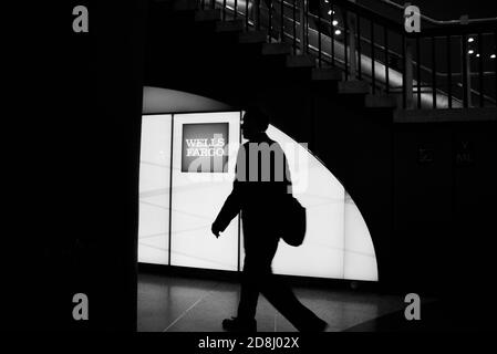 I viaggiatori camminano oltre il logo Wells Fargo a Penn Station, New York City, USA. Foto Stock