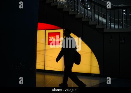 I viaggiatori camminano oltre il logo Wells Fargo a Penn Station, New York City, USA. Foto Stock